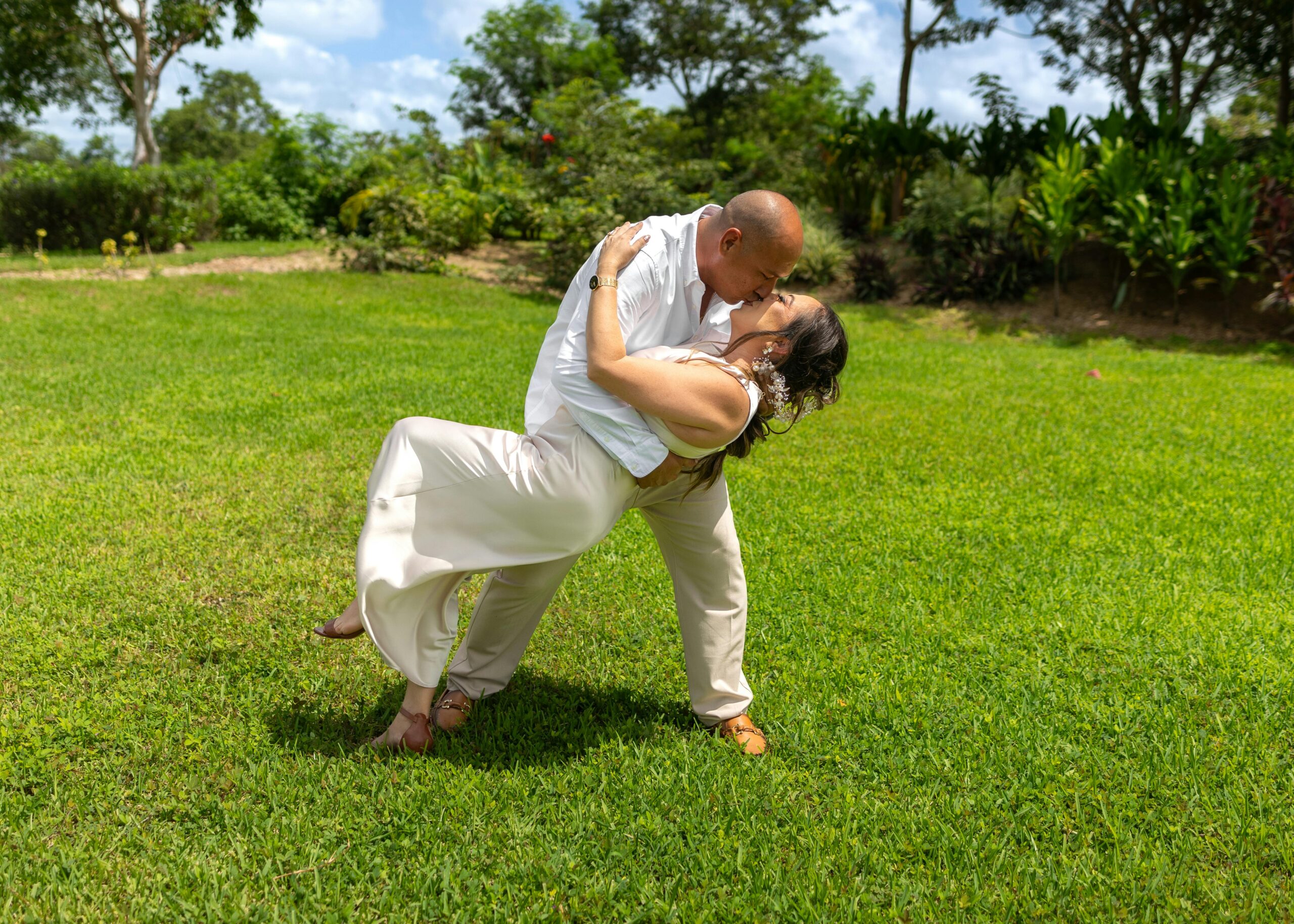 A couple shares a romantic dance in a lush garden in Mérida, Mexico, symbolizing love and happiness.